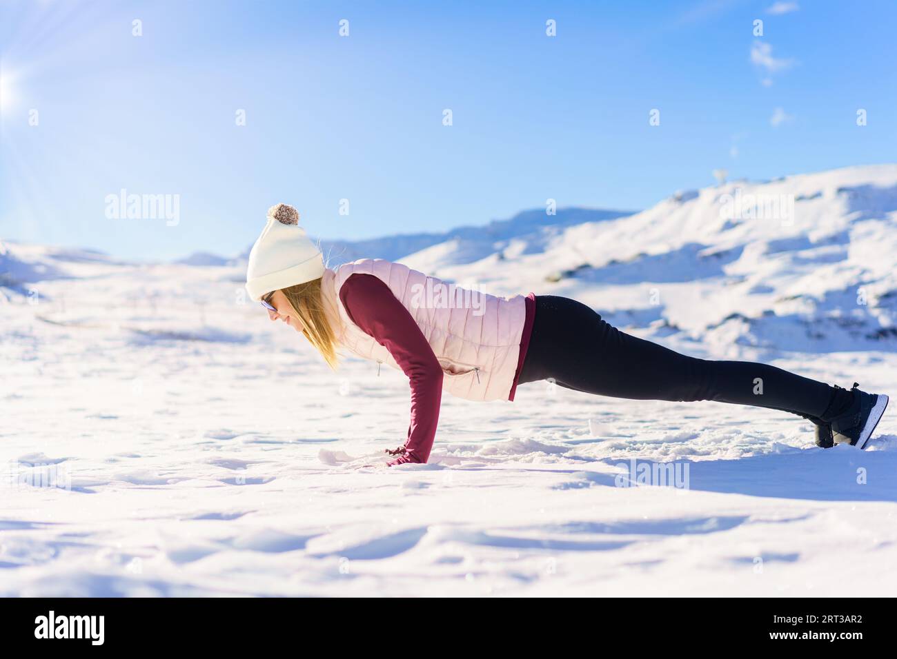 Jeune femme faisant handstand appuyez sur la neige Banque D'Images