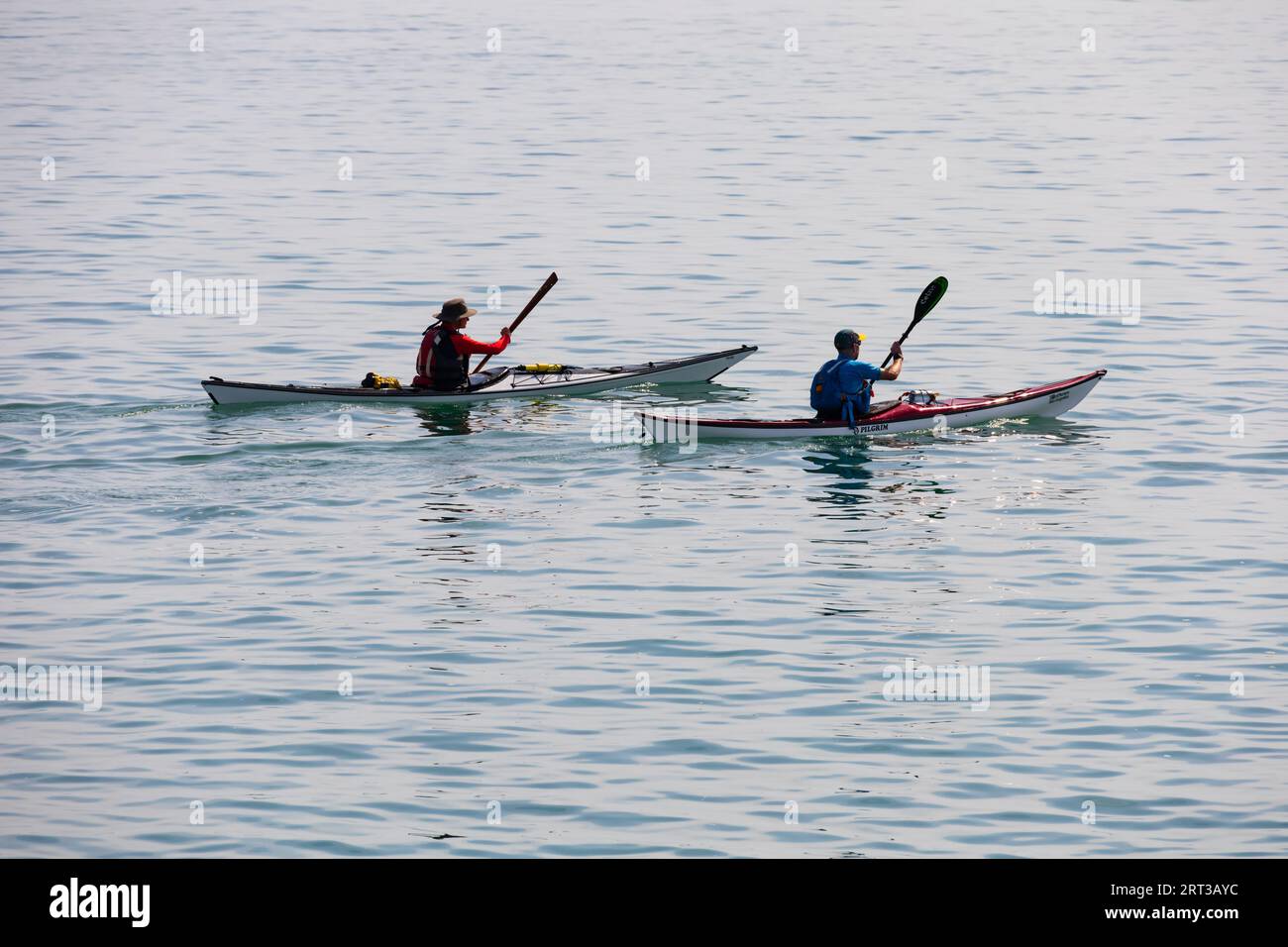 Des hommes dans deux kayaks de mer pagaient sur une mer calme. Bridport, Dorset. Journée la plus chaude de l'année. Banque D'Images