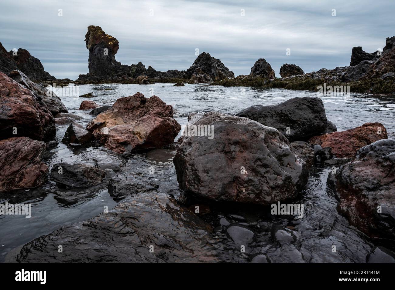 Bizarres formations rocheuses de lave noire et rochers de basalte volcanique dans les vagues sur la rive de la plage de Djúpalónssandur, Snæfellsnes, Islande Banque D'Images