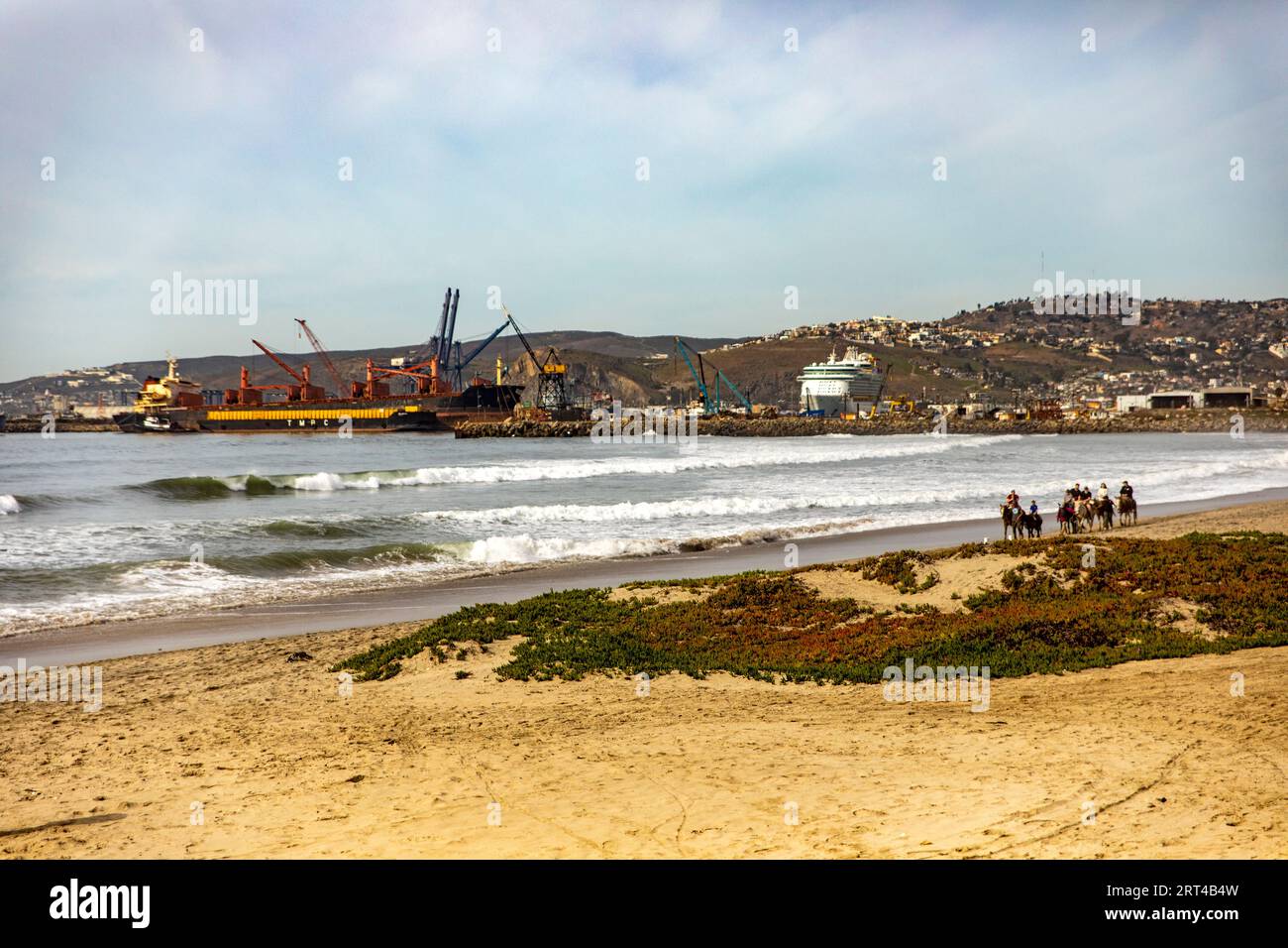 Une belle plage à Ensenada avec le port en arrière-plan et les gens à cheval par la mer, c'est l'un des meilleurs endroits touristiques de Baja Cali Banque D'Images