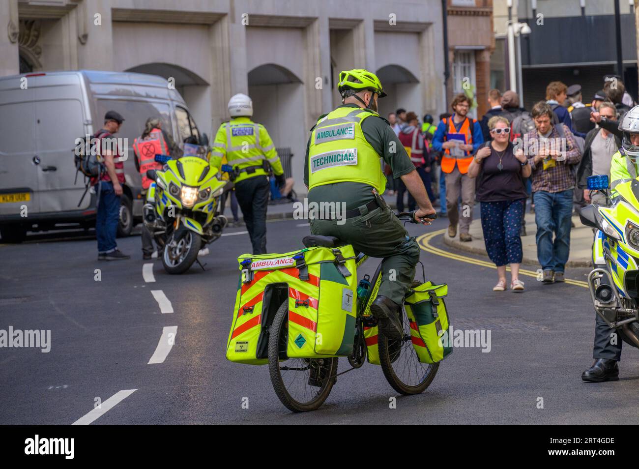 LONDRES - 22 avril 2023 : réponse à la protestation de Londres : un cycliste paramédical et une moto de police assistent à la marche XR, prêts à fournir une assistance d'urgence Banque D'Images