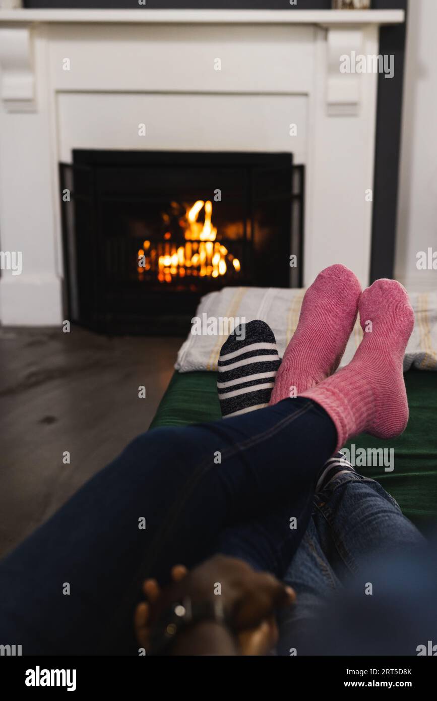 Pieds de couple en chaussettes se relaxant à la maison devant le feu ouvert Banque D'Images