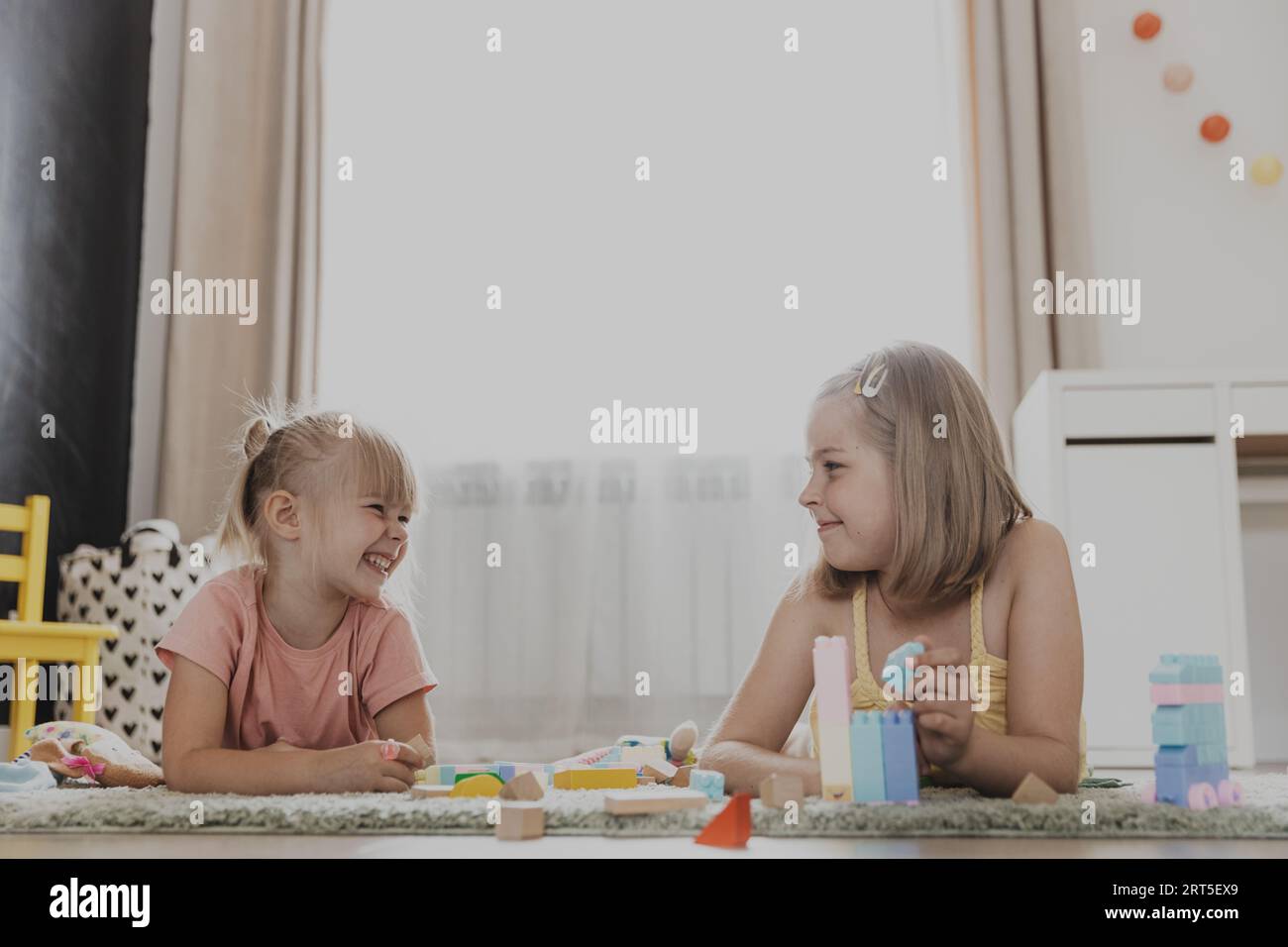 Enfants jouant avec des jouets colorés. Enfants assis sur la moquette dans la chambre à coucher ou la maternelle à la maison, la crèche. Jeu écologique éducatif pour enfant. Créatif heureux âge préscolaire enfant doux Banque D'Images
