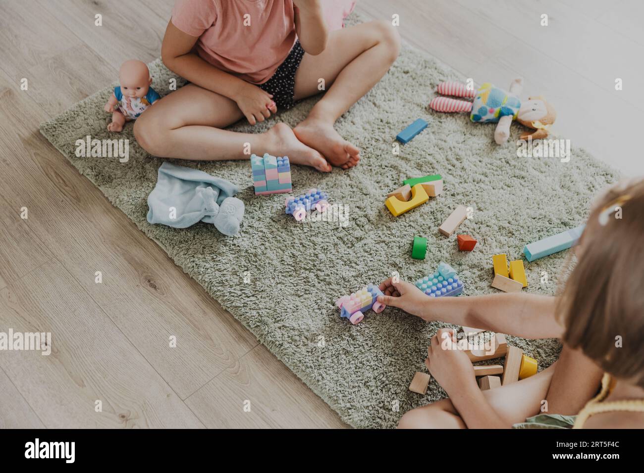 Enfants jouant avec le train coloré de jouet en plastique coloré. Les enfants assis sur le tapis à l'intérieur à la chambre à coucher blanche ensoleillée à la maison ou à la maternelle, garderie. Jeu amusant et écologique éducatif pour enfant Banque D'Images
