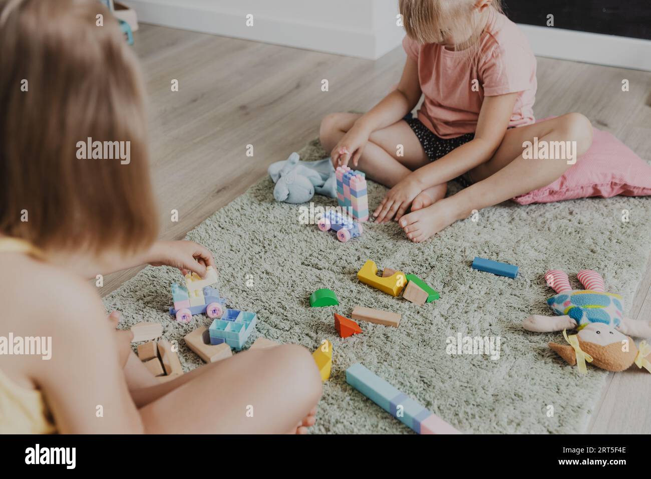 Enfants jouant avec train jouet en bois coloré. Enfants assis sur la moquette à la chambre à coucher à la maison, maternelle, salle de jeux de garderie, aire de jeux, centre de jeux. Jeu amusant et écologique éducatif pour enfant Banque D'Images