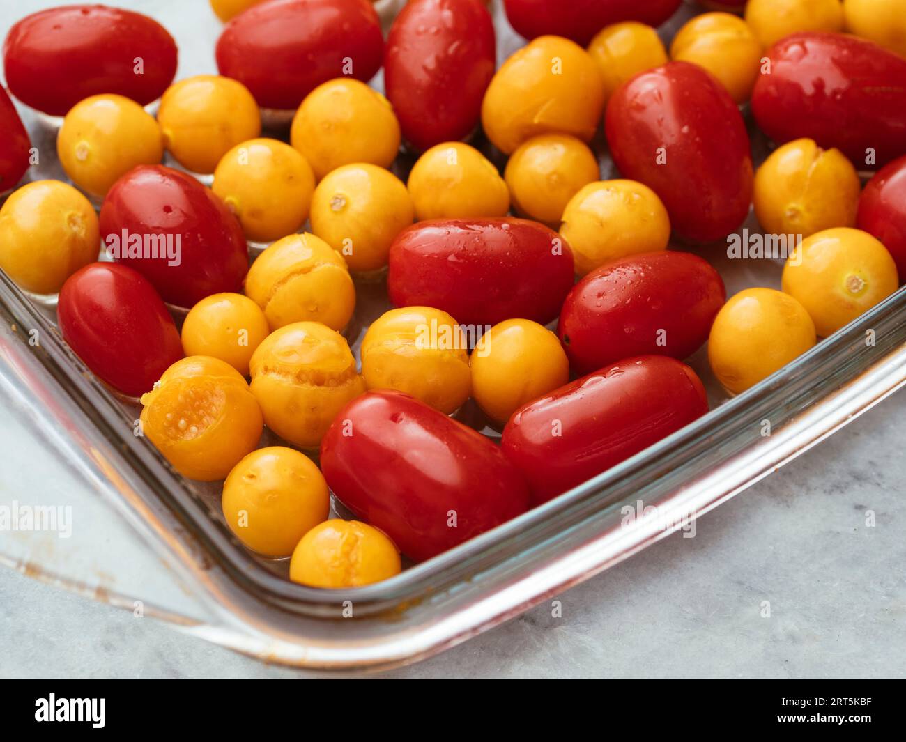 Tomates cerises et physalis dans un plat de cuisson avant de faire rôtir. Banque D'Images