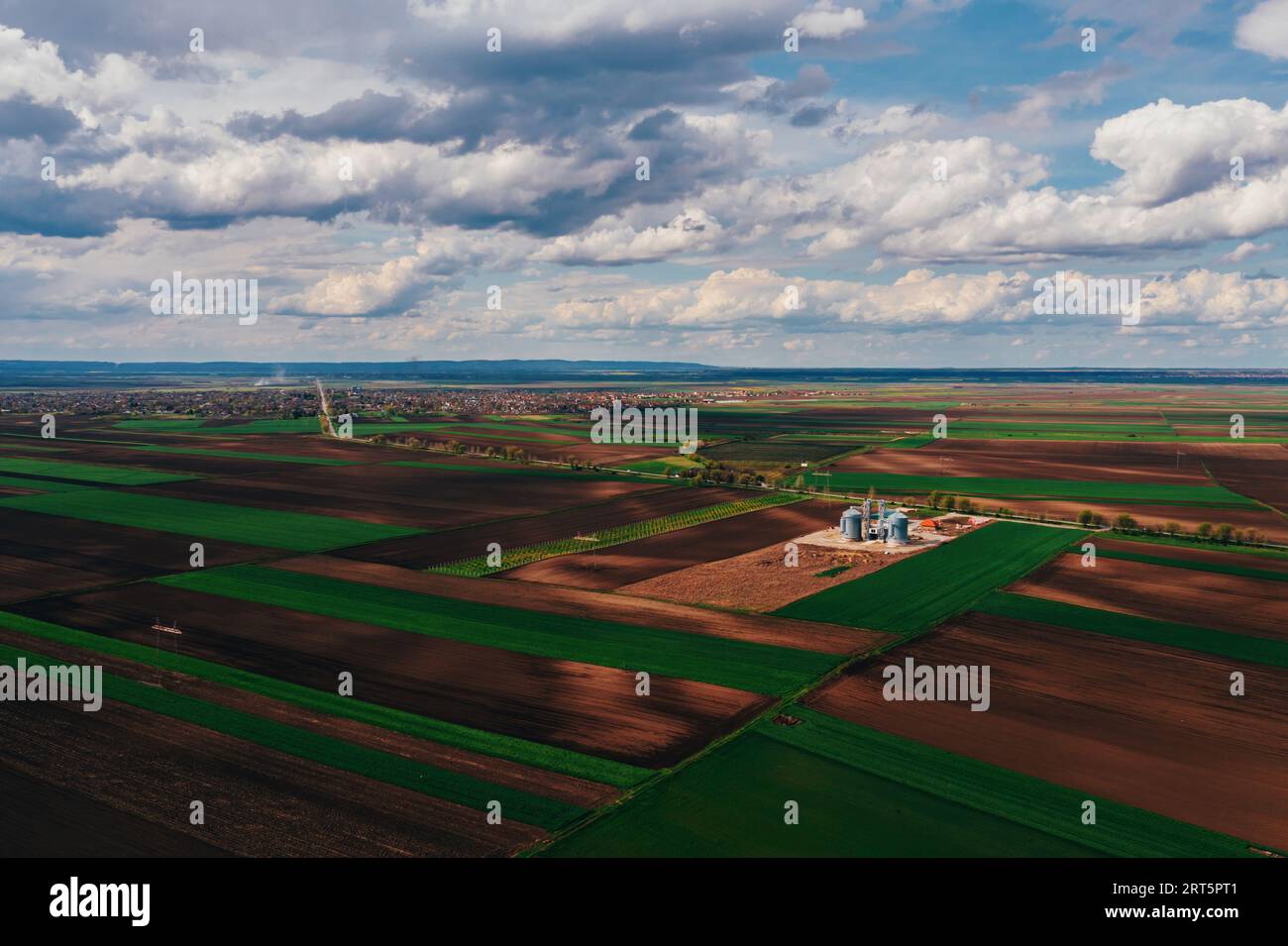 Silos de ferme dans le champ, vue aérienne du drone pov le jour ensoleillé de printemps avec des nuages blancs au-dessus de l'horizon Banque D'Images