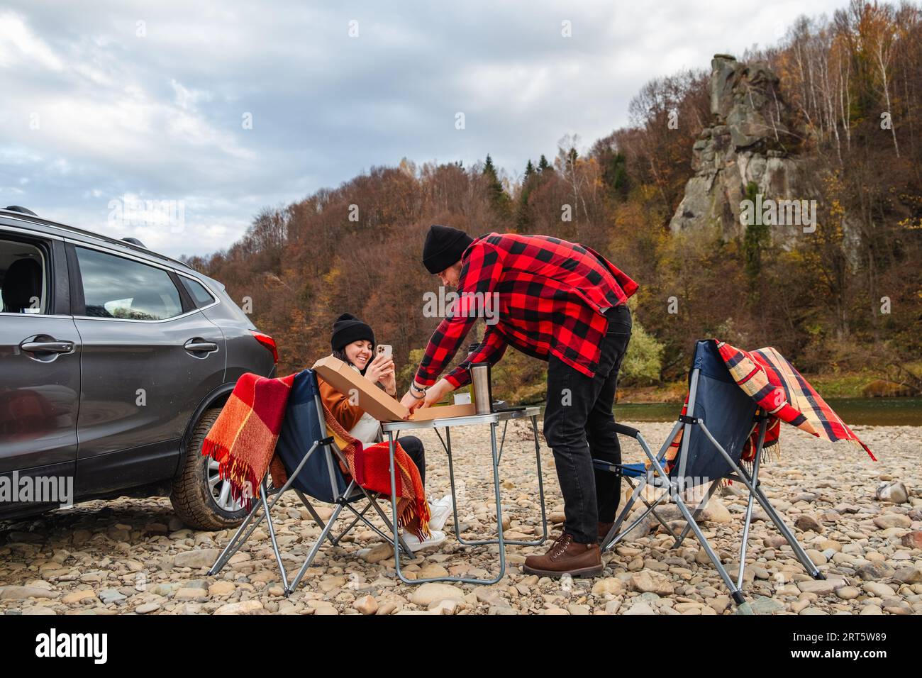 couple ayant pique-nique à la rivière de montagne d'automne Banque D'Images