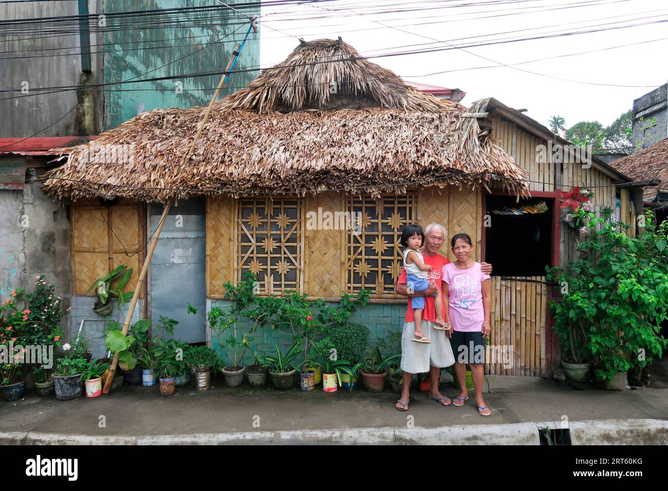 Grands-parents avec enfant devant une cabane en paille, ville de Legazpi, province d'Albay, Philippines Banque D'Images