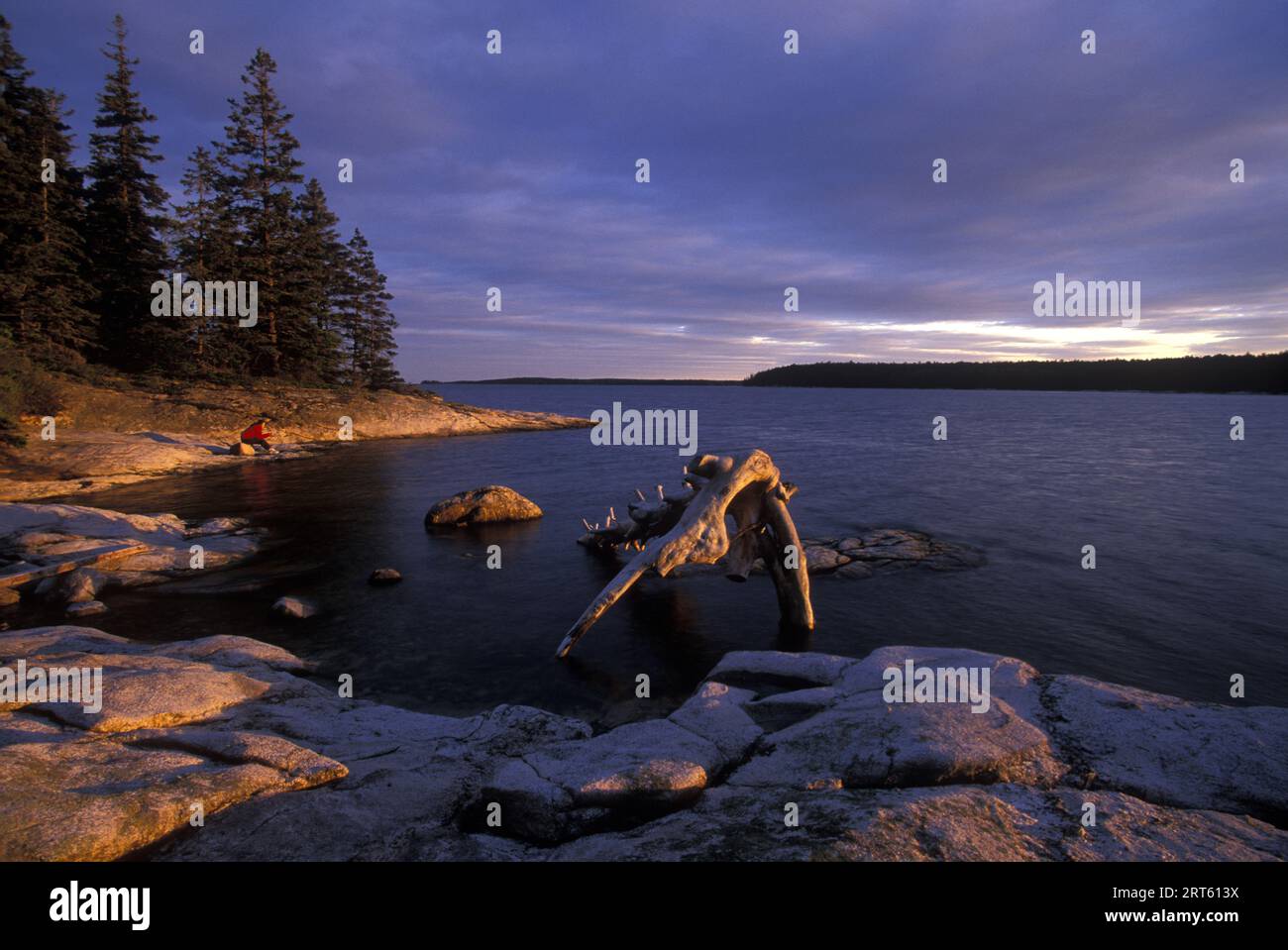 Un randonneur solitaire voit le coucher de soleil depuis l'île de Theif, Muscongus Bay, Maine. Banque D'Images