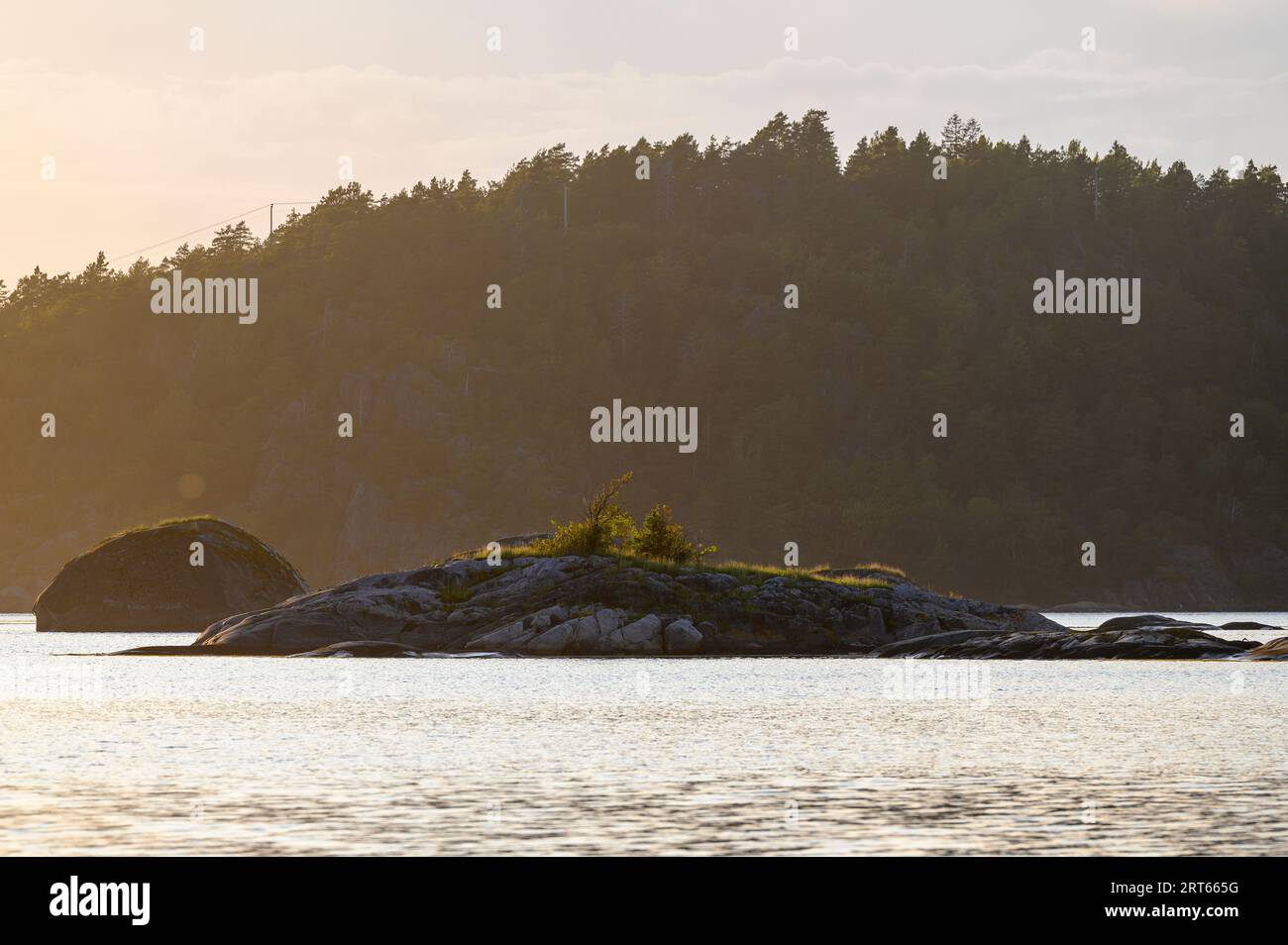 Îlots rocheux (skerries) en contre-jour du soleil du soir avec en toile de fond la plus grande île Gumoy dans l'archipel de Kragero, Telemark, Norvège. Banque D'Images