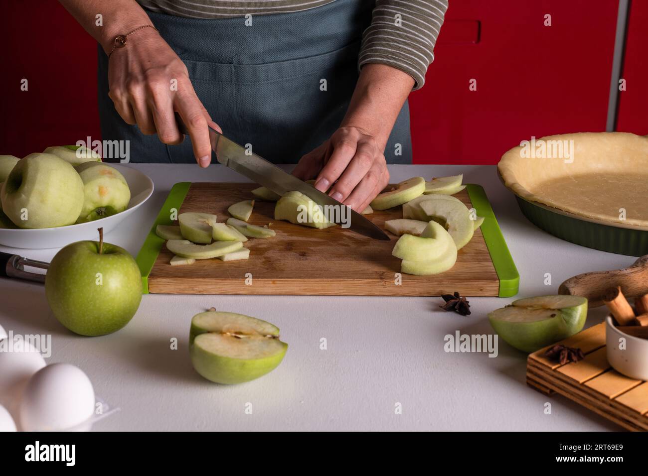 Femme tranchant des pommes sur une planche à découper en bois pour la tarte aux pommes. Préparation de Thanksgiving, boulangerie d'automne, traditions d'automne. Bonbons croustillants Banque D'Images