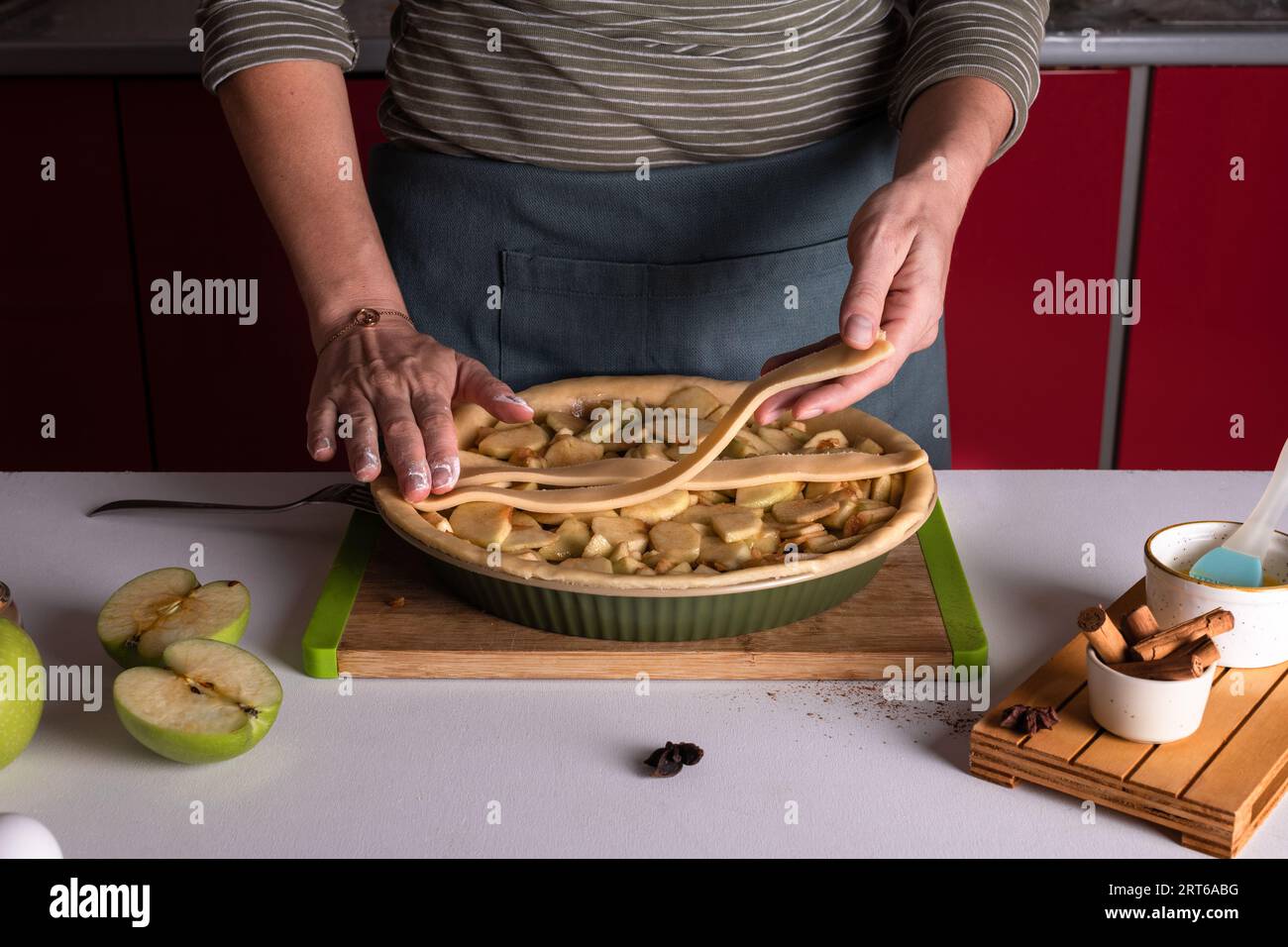 Femme plaçant la pâte à tarte sur le dessus de la tarte aux pommes dans le plat de boulangerie, prêt à être mis dans le four, préparant la tarte aux pommes. Préparation de tarte de Thanksgiving, A. Banque D'Images