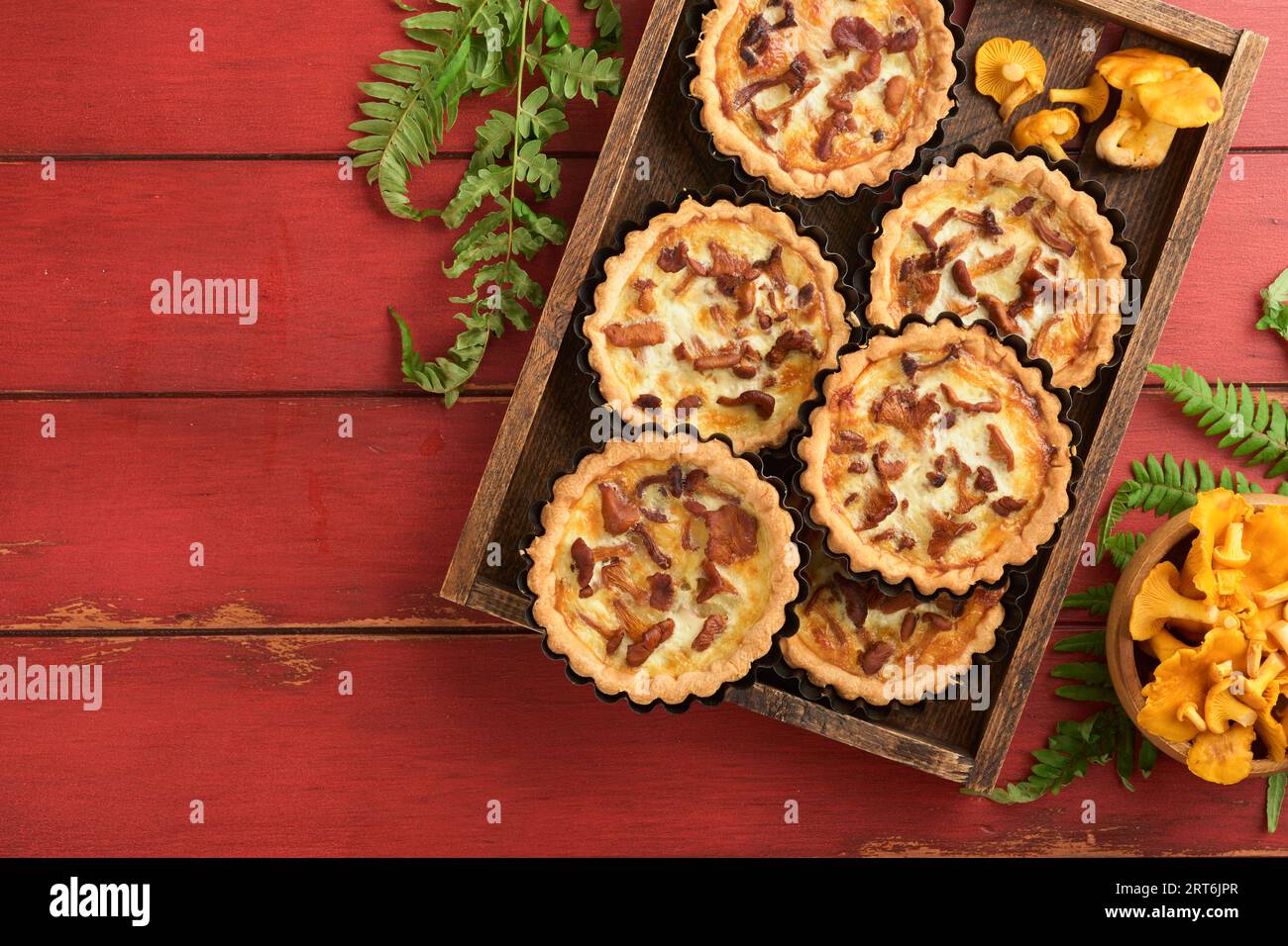 Tarte aux mains savoureuse avec des champignons chanterelles, crème et fromage sur une planche à découper sur fond de table en bois rouge rustique. Tartes maison avec saison Banque D'Images