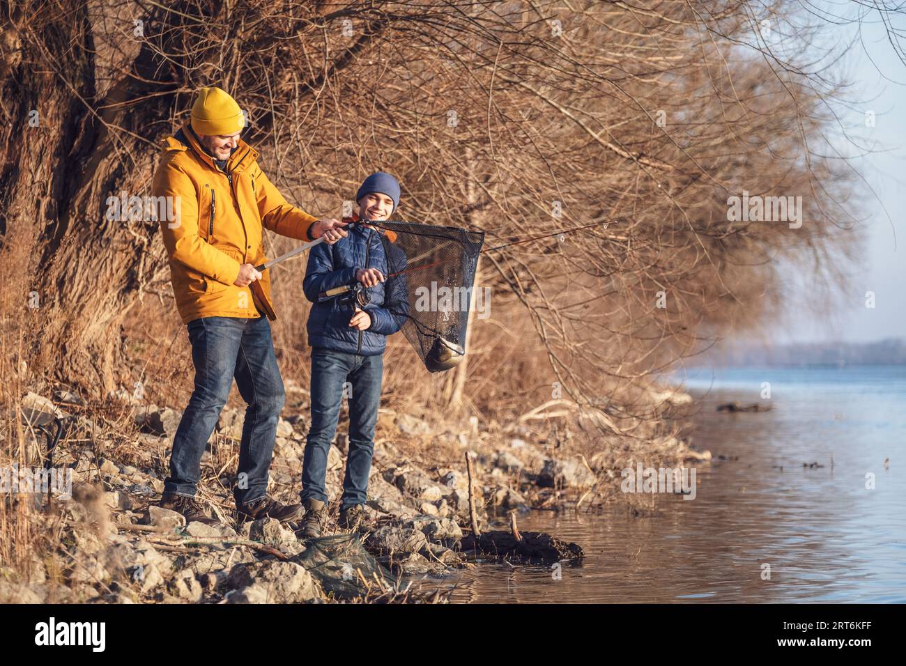 Le père et son fils pêchent le jour d'hiver ensoleillé. Ils ont attrapé un poisson et le tiennent dans un filet d'atterrissage. Banque D'Images