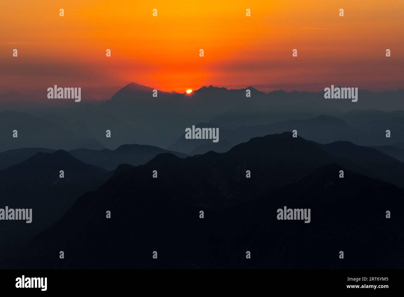 Vue pittoresque silhouette de paysage brumeux d'énormes montagnes rocheuses sous le ciel de coucher du soleil avec des nuages orange dans la frontière du lac majeur entre l'Italie et Banque D'Images