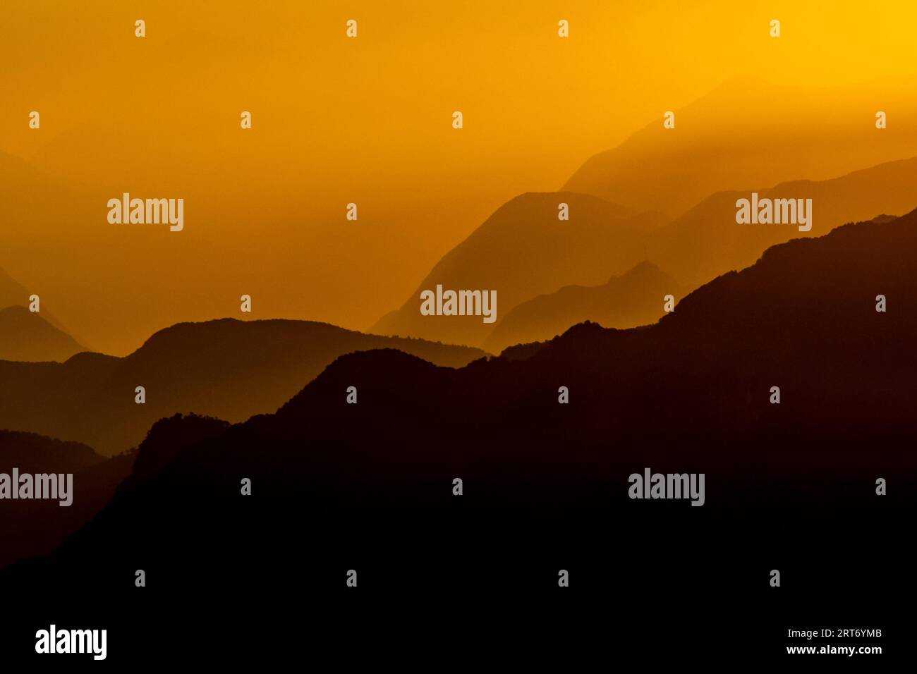 Vue pittoresque silhouette de paysage brumeux d'énormes montagnes rocheuses sous le ciel de coucher du soleil avec des nuages orange dans la frontière du lac majeur entre l'Italie et Banque D'Images