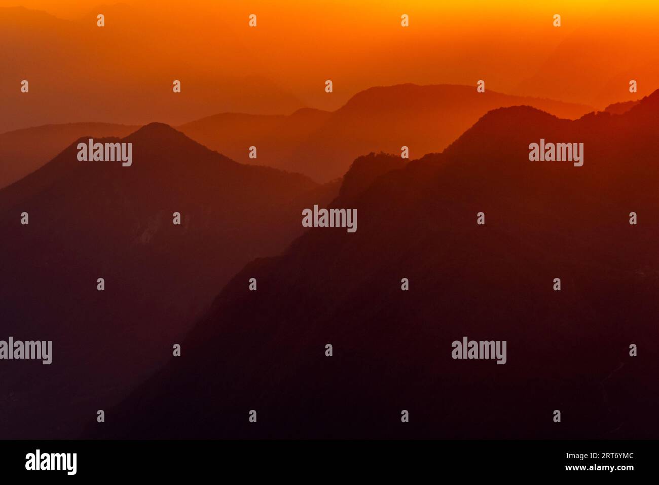 Vue pittoresque silhouette de paysage brumeux d'énormes montagnes rocheuses sous le ciel de coucher du soleil avec des nuages orange dans la frontière du lac majeur entre l'Italie et Banque D'Images