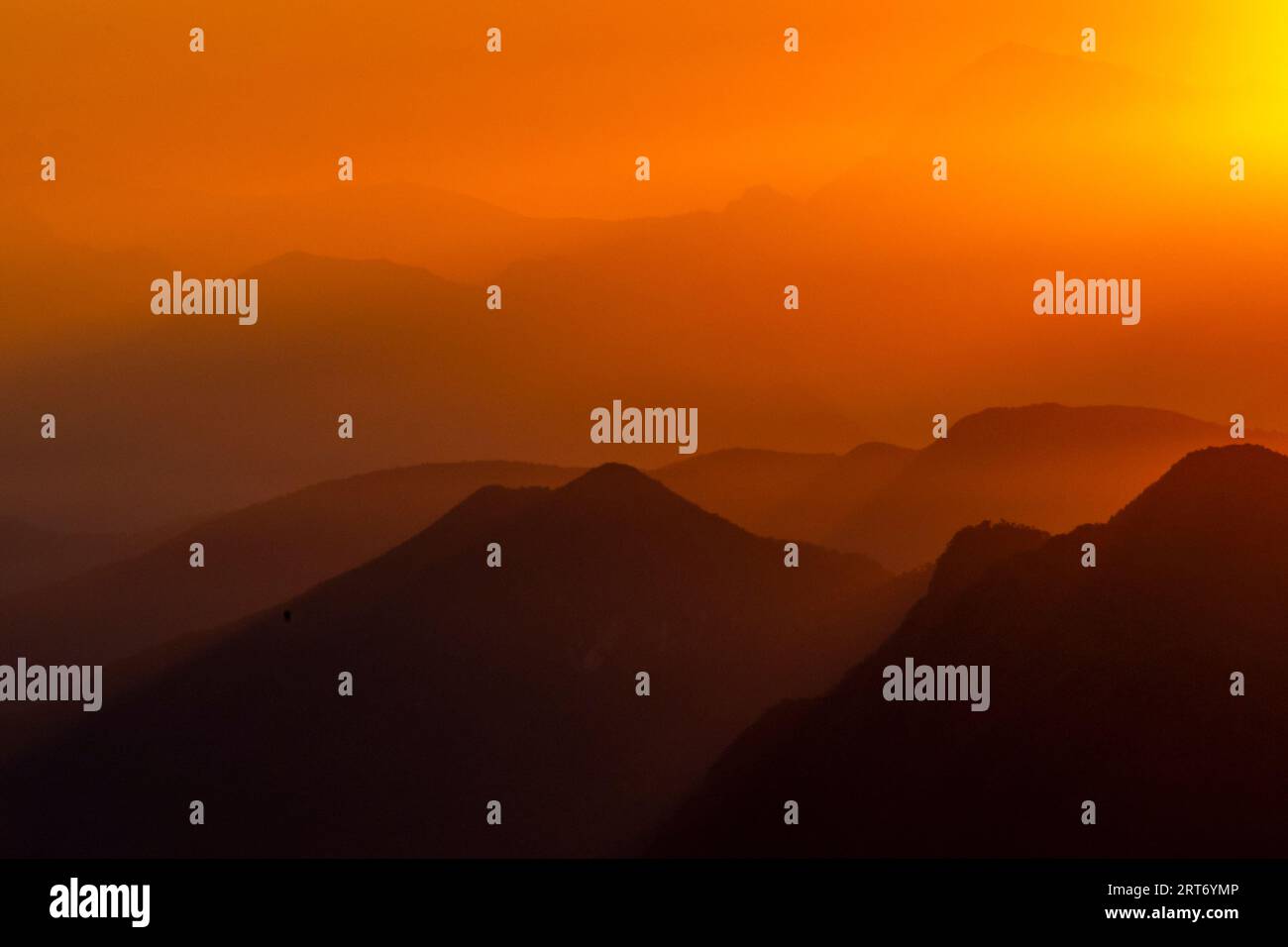 Vue pittoresque silhouette de paysage brumeux d'énormes montagnes rocheuses sous le ciel de coucher du soleil avec des nuages orange dans la frontière du lac majeur entre l'Italie et Banque D'Images