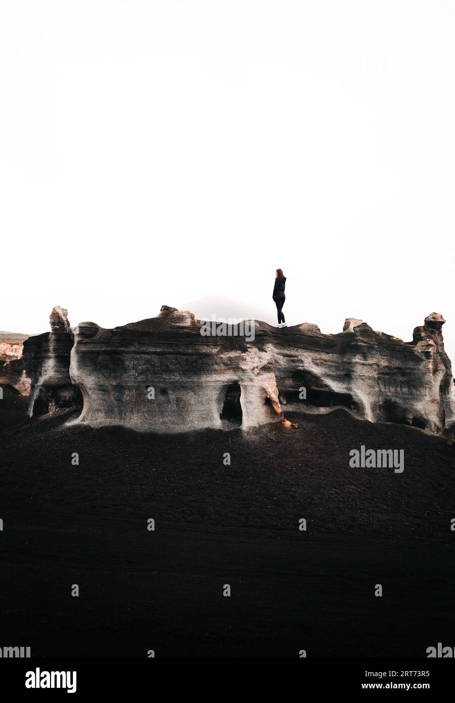 Photo verticale minimaliste de touriste femme debout sur le sommet de la roche dans le désert. Roches stratifiées (teseguite - Lanzarote) avec voyageur sur le dessus en d Banque D'Images