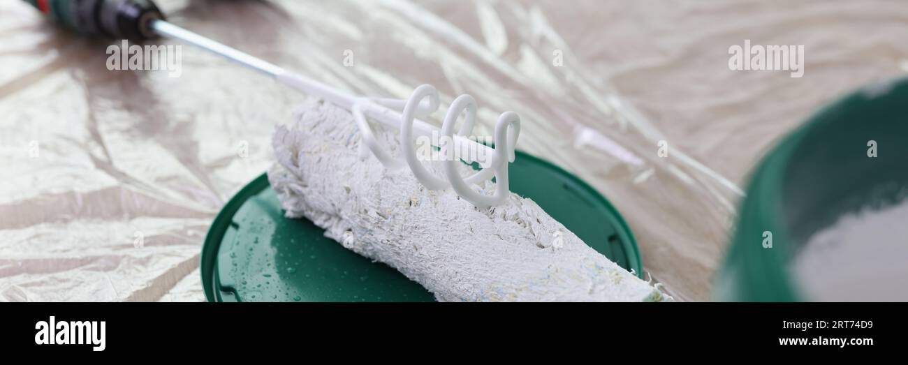 Mélangeur de peinture, brosse rotative et seau avec peinture blanche sur plancher couvert. Banque D'Images