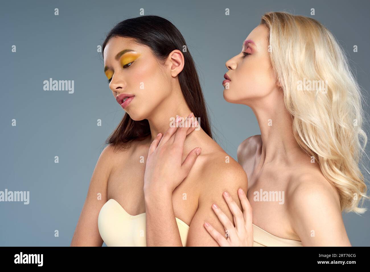 divers jeunes modèles avec maquillage des yeux vibrant posant ensemble sur fond bleu, concept de tendance de beauté Banque D'Images