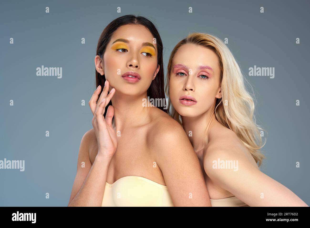 divers jeunes modèles avec maquillage des yeux audacieux posant ensemble sur fond bleu, concept de tendance de beauté Banque D'Images