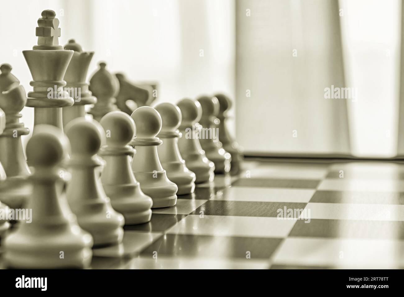 Figures d'échecs blanches sur l'échiquier teintées de couleur or foncé. Échecs conceptuels et arrière-plans d'activités de loisirs Banque D'Images
