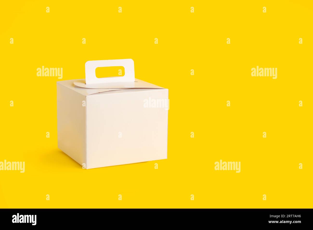 Une boîte en carton blanc sur fond jaune avec espace de copie Banque D'Images