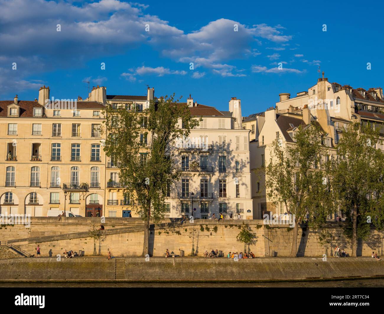 Lumière du soir, Appartements et personnes se détendant sur la rive, Seine, Île Saint-Louis, Paris, France, Europe, UE. Banque D'Images