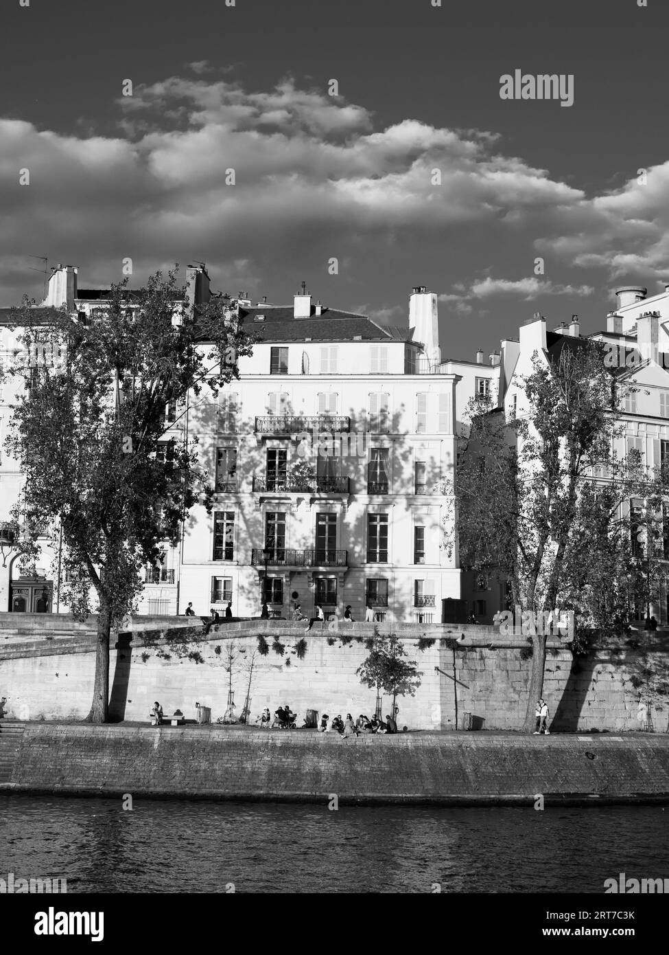 Noir et blanc, lumière du soir, Appartements et personnes se relaxant sur la rive, Seine, Île Saint-Louis, Paris, France, Europe, UE. Banque D'Images