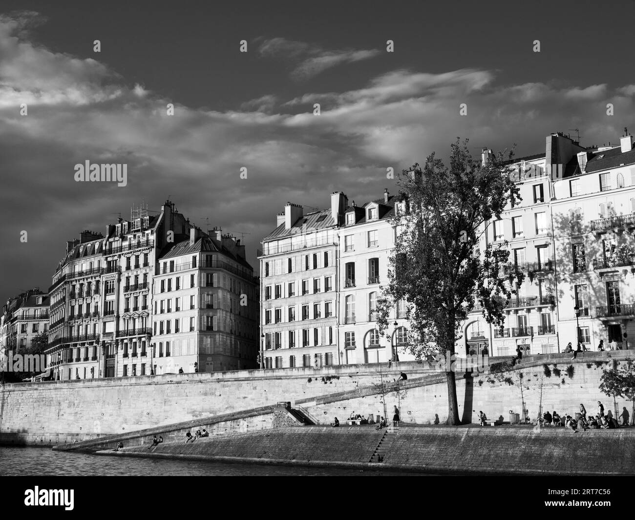 Noir et blanc, lumière du soir, Appartements et personnes se relaxant sur la rive, Seine, Île Saint-Louis, Paris, France, Europe, UE. Banque D'Images