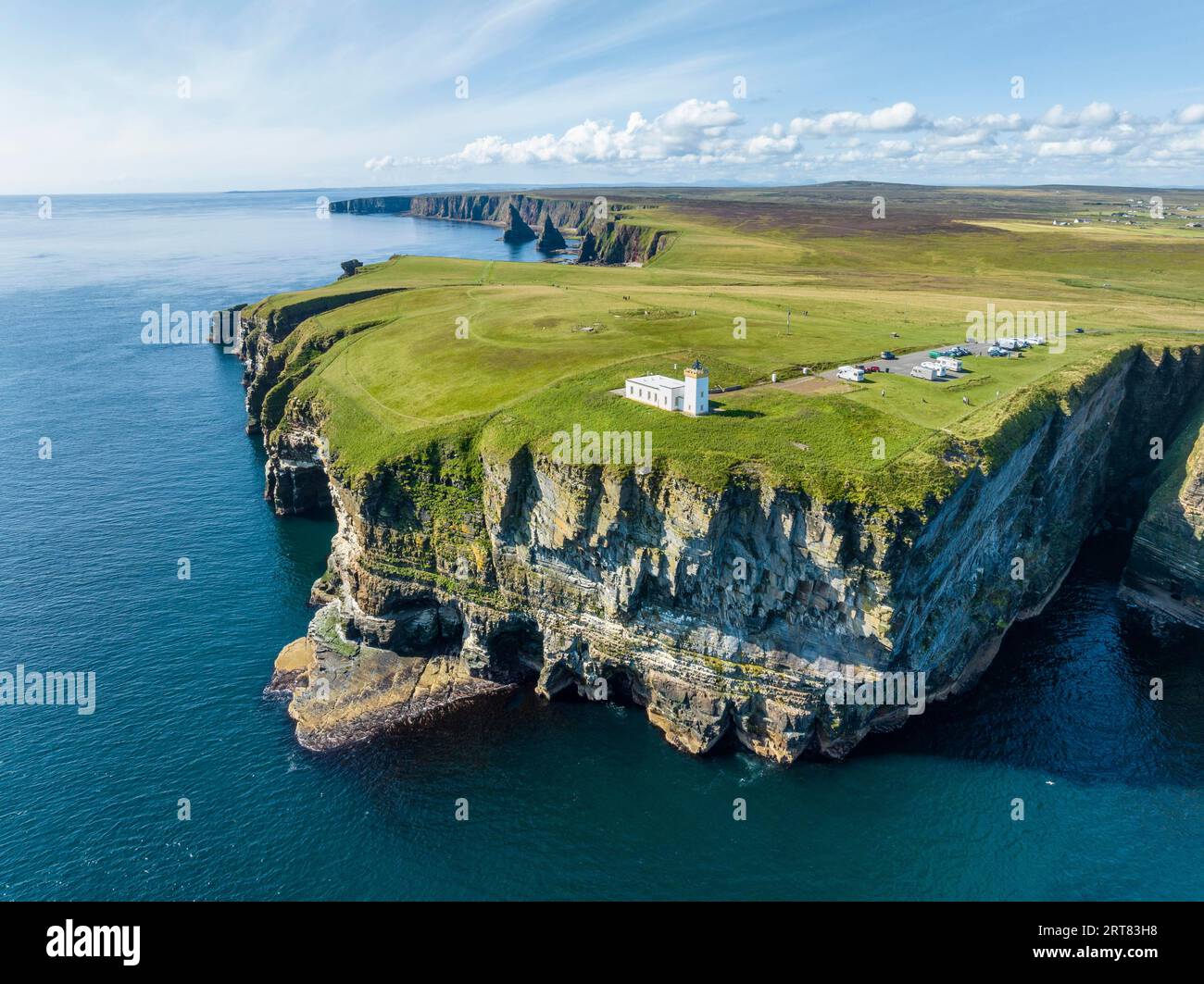 Vue aérienne du paysage côtier accidenté à Duncansby Head avec le phare et la formation rocheuse Duncansby empilée derrière, en Écosse Banque D'Images