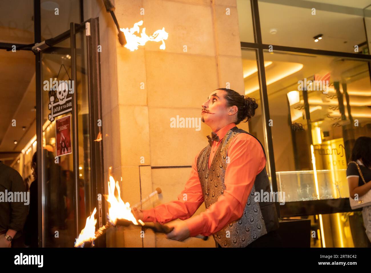 Jongleur à une fête d'halloween jonglant des bâtons avec le feu, à l'entrée de la discothèque Banque D'Images