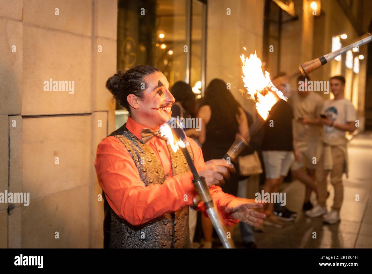 Jongleur à une fête d'halloween jonglant des bâtons avec le feu, à l'entrée de la discothèque Banque D'Images
