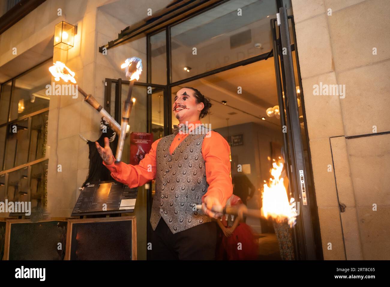 Jongleur à une fête d'halloween jonglant des bâtons avec le feu, à l'entrée de la discothèque Banque D'Images