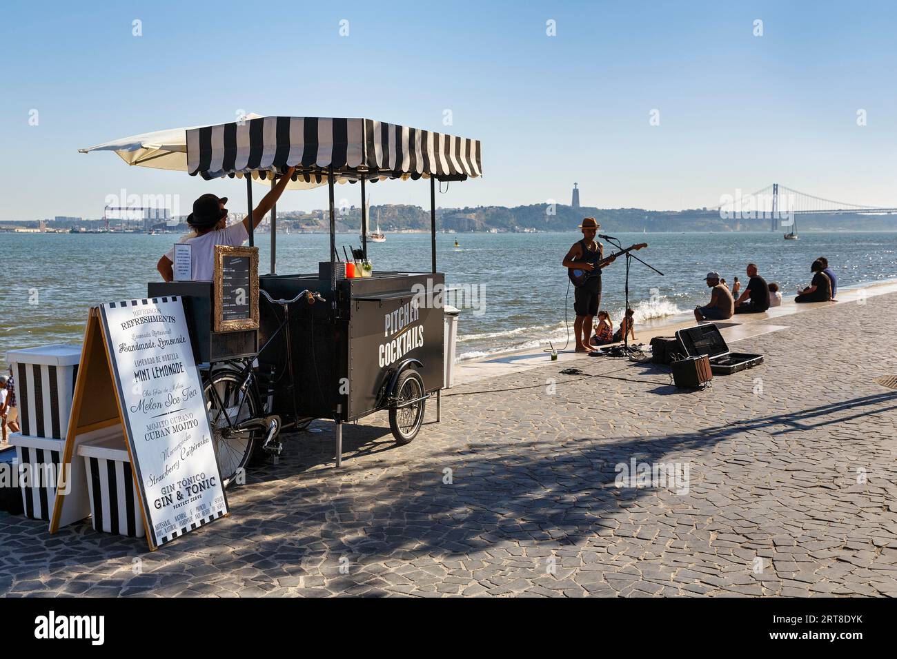 Terrasse animée sur les rives du Tage, kiosque à boissons, musiciens de rue rétroéclairés, Ribeira das Naus, Lisbonne, Portugal Banque D'Images