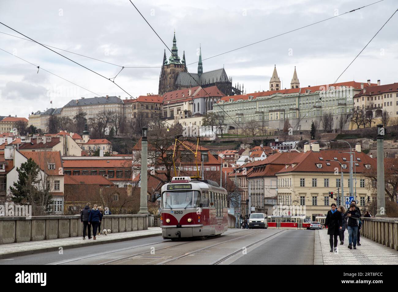 Prague, République tchèque, 20 mars 2017 : un tramway rouge et des gens sur un pont avec le château de Prague en arrière-plan Banque D'Images