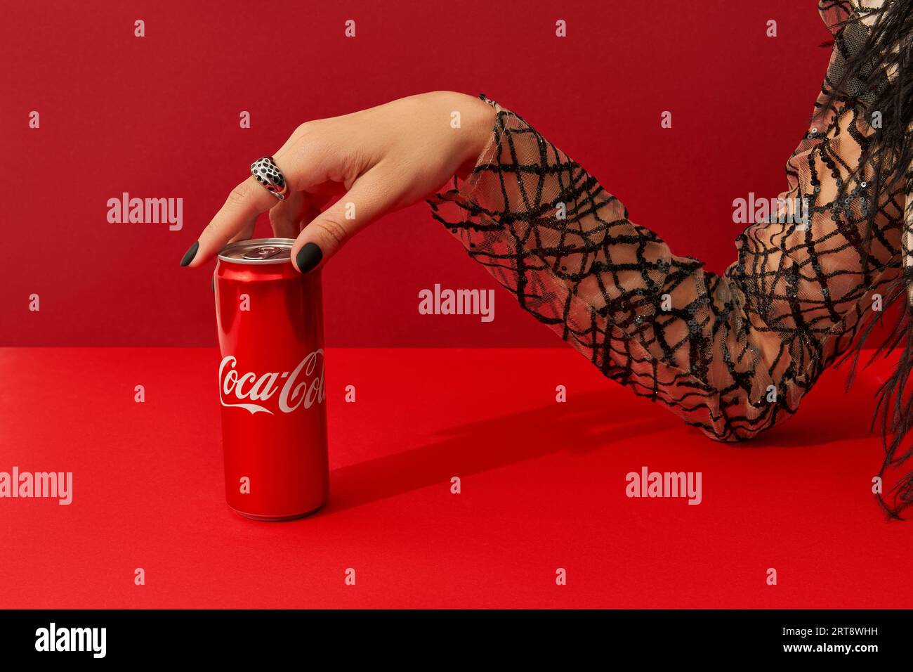 Ukraine, Kiev 6 août 2021, main de Womans avec la conception d'ongle effrayante prend CAN de boisson Coca cola sur fond rouge. Banque D'Images