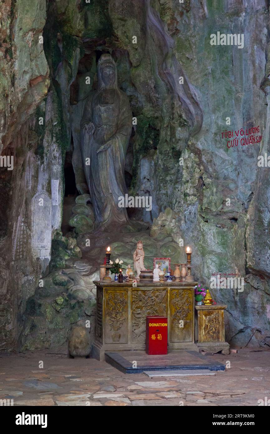 Petit sanctuaire devant une statue de Guanyin directement sculptée dans la pierre de marbre à l'entrée de la grotte de Huyen Khong à Da Nang. Banque D'Images