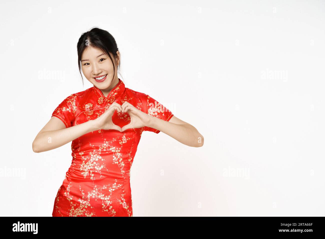 Femme asiatique portant la robe traditionnelle cheongsam qipao faisant une forme de coeur avec sa main isoler sur fond blanc.bonne année chinoise. Banque D'Images