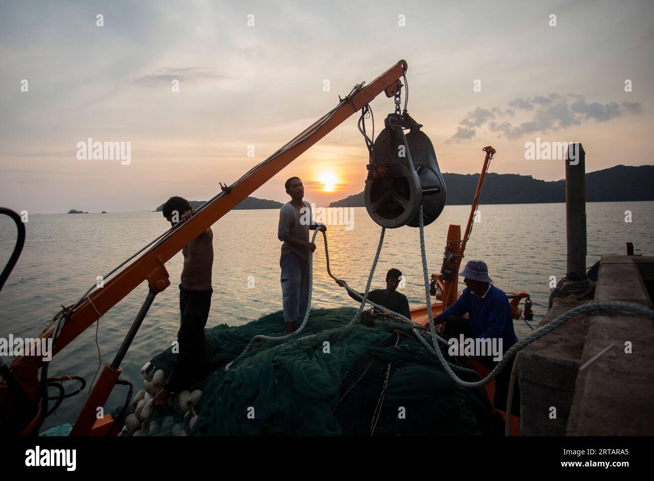 Koh Yao, Thaïlande ; 1 janvier 2023 : les pêcheurs déchargent les prises de la journée d'un bateau dans le port de Koh Yao au coucher du soleil. Banque D'Images