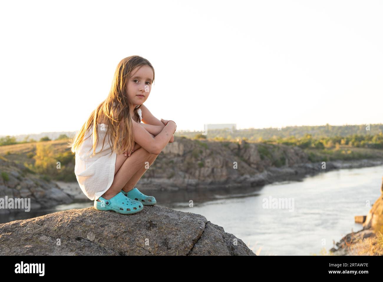 Offensée fille triste de cinq ans assise sur des rochers dans la nature seule. Banque D'Images