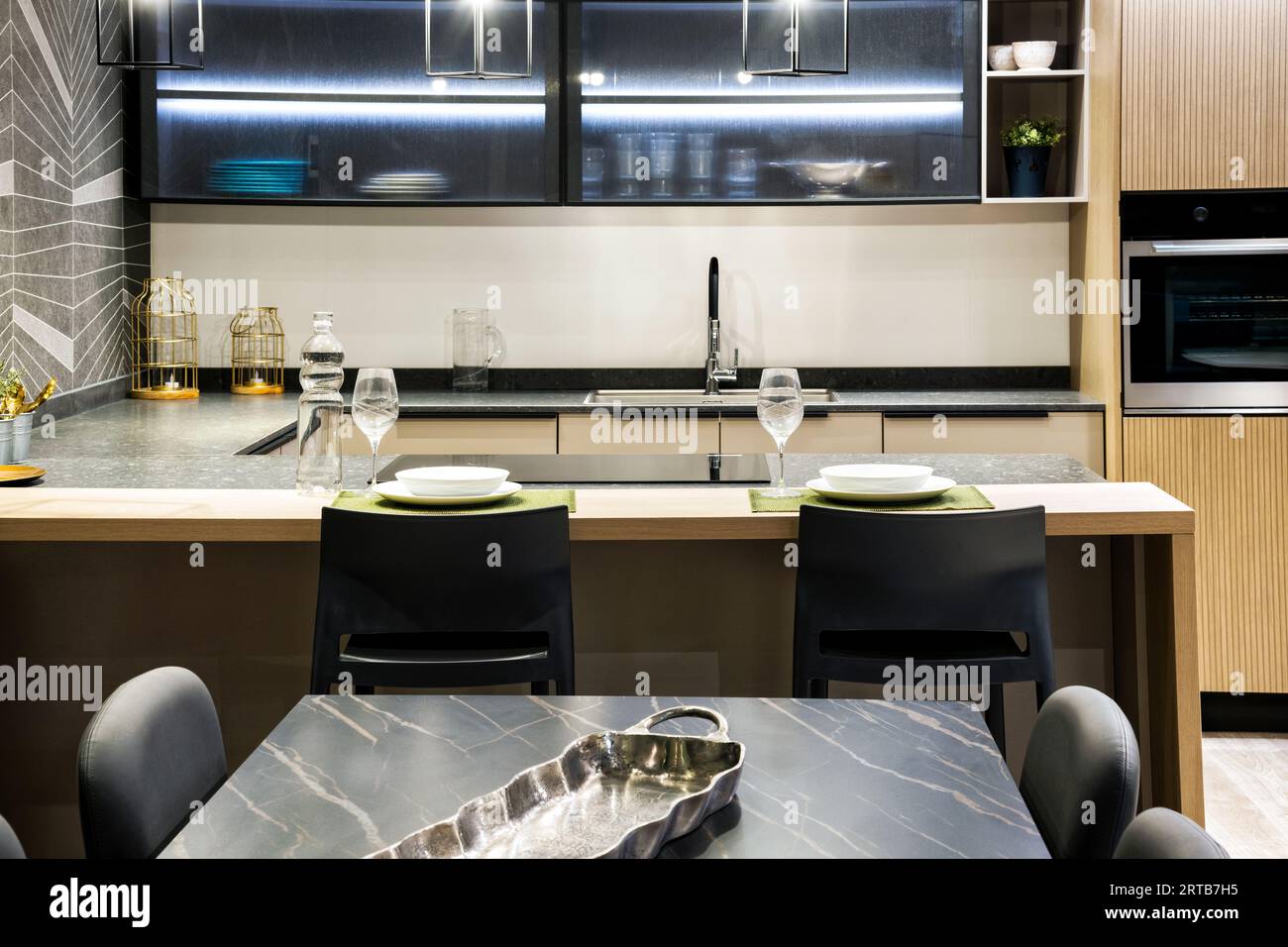 Intérieur de la cuisine moderne meublée avec des appareils intégrés étagères de four ustensiles de cuisine bouteille d'eau potable verres transparents près du poêle tandis que dini Banque D'Images