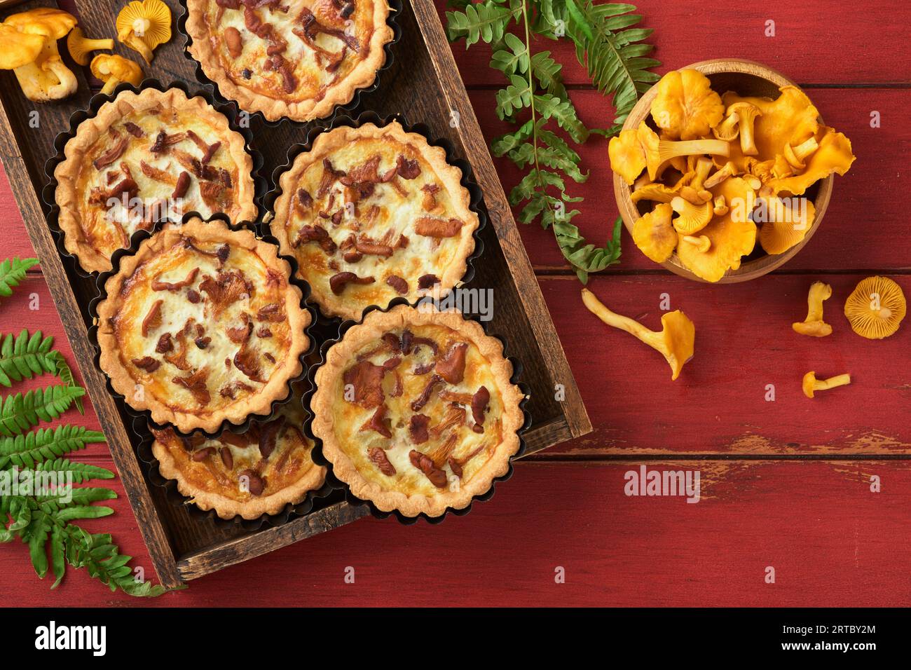 Tarte aux mains savoureuse avec des champignons chanterelles, crème et fromage sur une planche à découper sur fond de table en bois rouge rustique. Tartes maison avec saison Banque D'Images