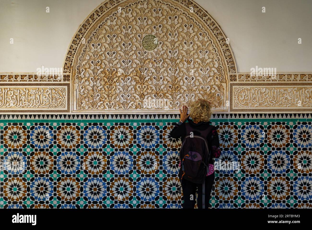 Afrique du Nord. Maroc. Marrakech. Madrasa Ben Youssef. La madrassah la plus grande et la plus importante du Maroc. Femme touriste regarde l'écriture coranique Banque D'Images