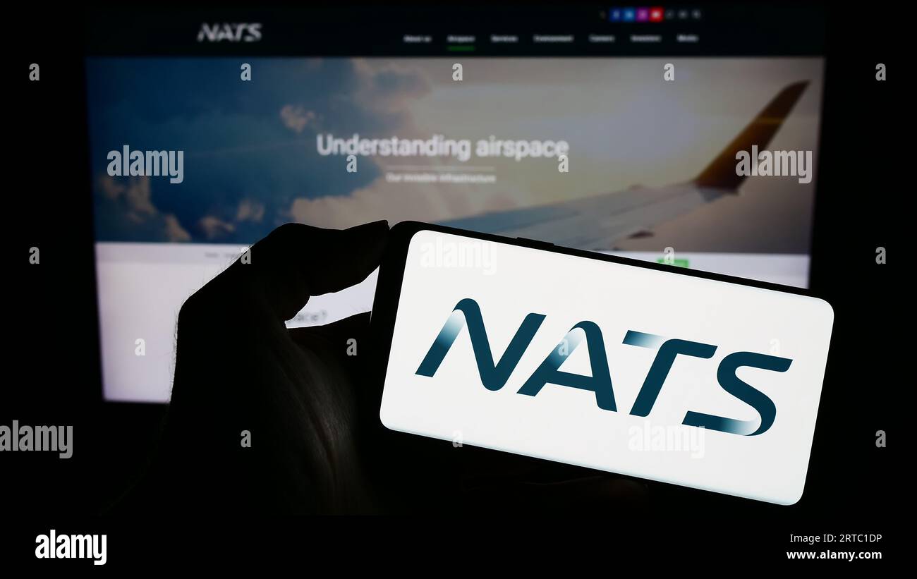 Personne détenant un téléphone portable avec le logo de l'opérateur britannique de contrôle du trafic aérien NATS Limited sur l'écran devant la page Web. Concentrez-vous sur l'affichage du téléphone. Banque D'Images