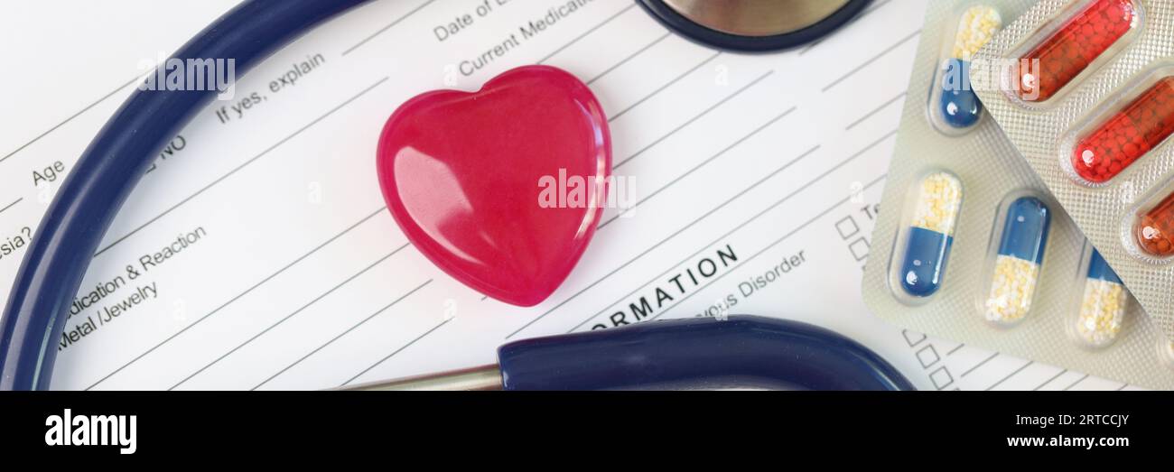 Les antécédents médicaux du patient se forment avec le cœur rouge, le stéthoscope et les paquets de pilules gros plan. Banque D'Images