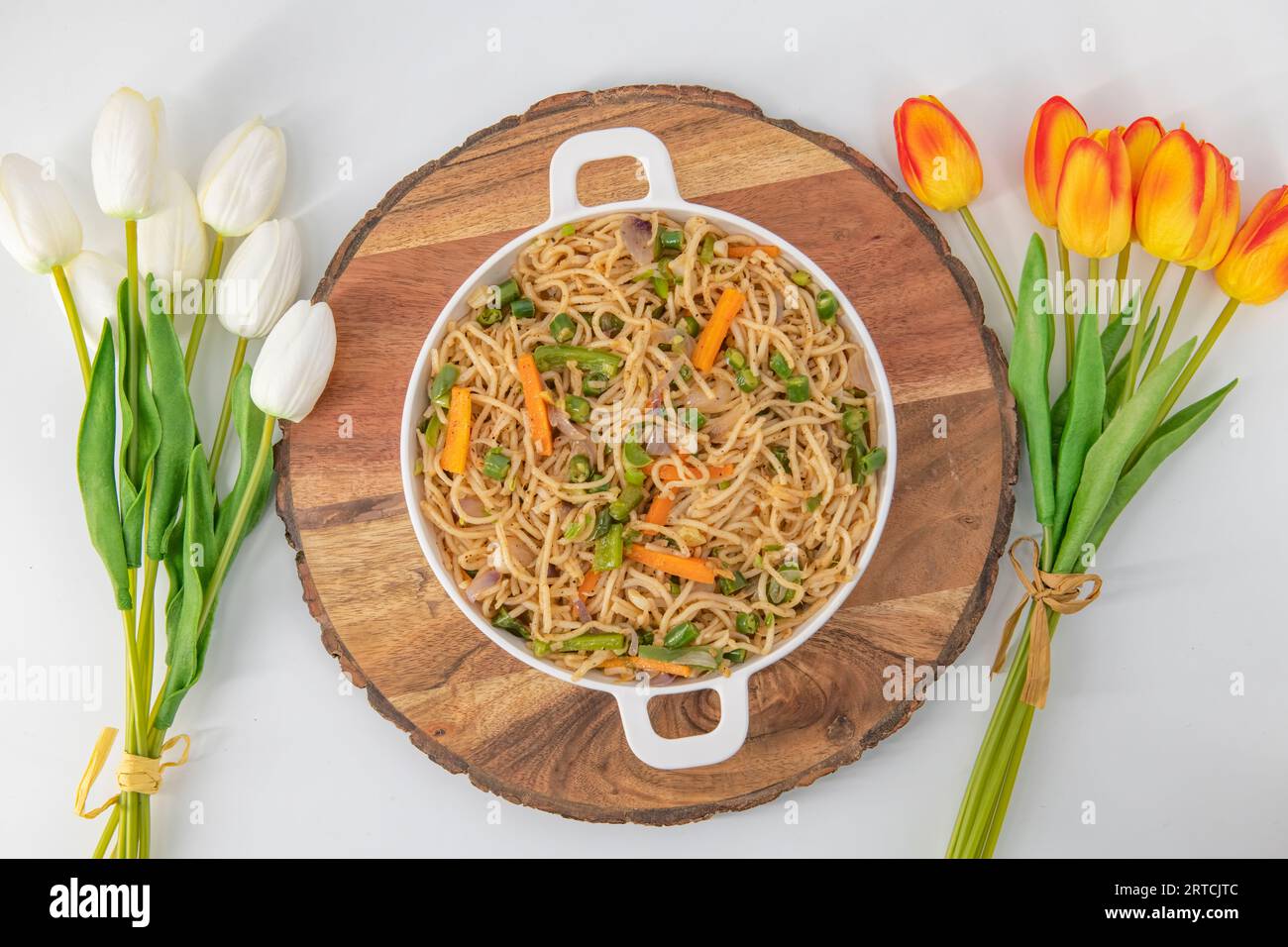 Savoureuses nouilles hakka aux légumes dans une assiette blanche et un fond isolé. Plat de cuisine végétarienne indo-chinoise. Nouilles végétales indiennes avec légumes. Banque D'Images