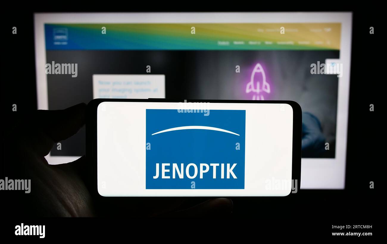 Personne tenant le téléphone portable avec le logo de la société allemande de photonique Jenoptik AG sur l'écran en face de la page Web de l'entreprise. Concentrez-vous sur l'affichage du téléphone. Banque D'Images